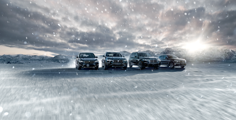 A line of BMWs driving through the snow