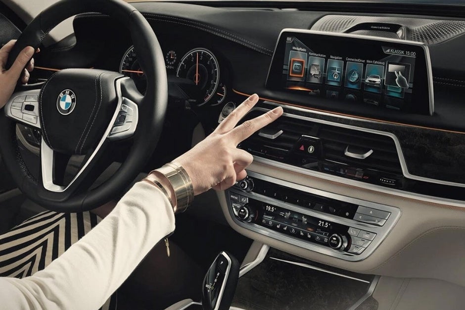 woman in the drivers seat of a BMW holding the peace sign up facing the stereo system